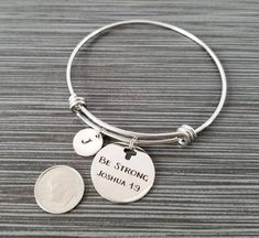 "Be Strong and Courageous - Joshua 1:9 Personalized Initial Bangle Bracelet! A round charm printed with \"Be Strong and Courageous - Joshua 1:9\" on a stainless steel expandable bangle bracelet makes the perfect gift for you or a loved one. The religious bracelet charm is made from stainless steel and measures 24 mm by 24 mm. The bible verse bracelet is high quality stainless steel and fits a wrist sized 6-8\". The bangle bracelet is personalized with a .5\" silver plated disc stamped with the i Inspirational Adjustable Round Jewelry, Inspirational Round Adjustable Jewelry, Inspirational Adjustable Silver Charm Bracelet, Verse Bracelet, Initial Bangle Bracelet, Bible Verse Bracelet, Bible Verse Jewelry, Expandable Bangle Bracelet, Bracelet Initial