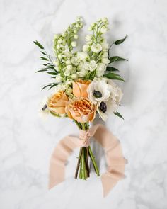 a bouquet of flowers on a marble surface with a pink ribbon tied around the stems