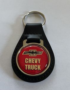 a red and black keychain with the words chevy truck on it's side