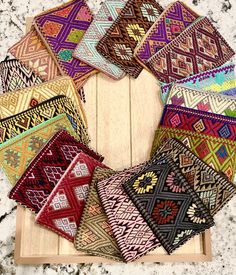 a bunch of different colored rugs sitting on top of a wooden table