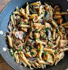 pasta with mushrooms and parsley in a skillet on a wooden table top, ready to be eaten