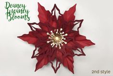 a paper poinsettia on a white background with the words denney blooming above it