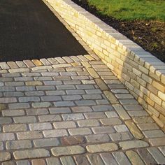 a brick walkway with grass and bushes in the background