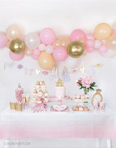 a table topped with lots of pink and gold balloons