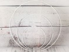 three metal circles sitting on top of a white table next to a wooden wall and floor