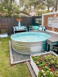 an above ground pool surrounded by plants and seating area in a backyard with wooden fence