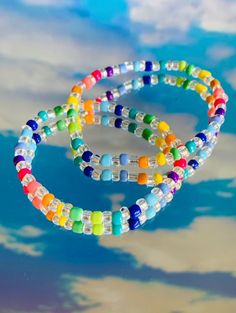 two bracelets with multicolored glass beads on a blue sky and clouds background