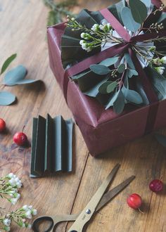 a pair of scissors sitting on top of a wooden table next to a wrapped present