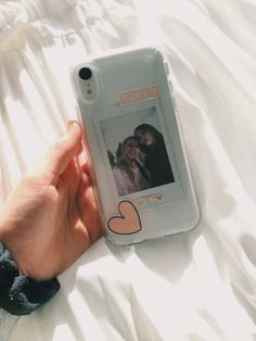 someone is holding their cell phone with an image on the back and heart drawn on it