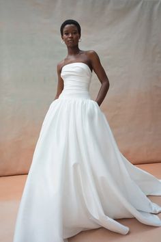 a woman in a white wedding dress poses for the camera with her hands on her hips