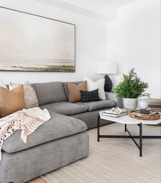 a living room filled with furniture and a large painting on the wall above it's coffee table