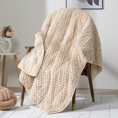 a white blanket sitting on top of a wooden chair