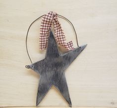 a wooden star ornament with a gingham ribbon hanging from it's side