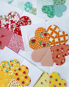 several pieces of heart shaped quilting on a white tablecloth with red, yellow and green flowers