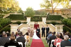 an outdoor wedding ceremony with red carpet and white chairs