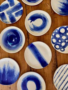 several blue and white plates sitting on top of a wooden table next to each other