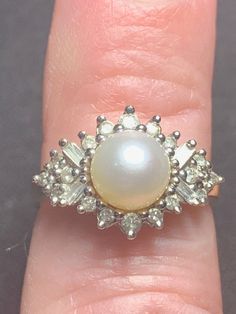 Exquisite vintage Diamond and Pearl ring crafted in 14K yellow gold. Featuring a white pearl  with vibrant lustre, The ring is complemented with diamonds consisting of round and baguette cut diamonds.  22 Diamonds weigh apx. .75 carats.   Currently a US size 7 and sizeable.  Excellent Condition.    Vintage pre-owned in very good condition. The finest quality of natural pearls have been highly valued as gemstones and objects of beauty for many centuries. Because of this, pearl has become a metaphor for something rare, fine, admirable and valuable. Pearls are the most time-honored and traditional of the June birthstones. Classic Pearl Ring With Diamond, Classic Pearl Ring With Diamond Center Stone, Formal Cluster Ring With Baguette Diamonds, Formal Baguette Diamond Cluster Ring, Vintage White Pearl Ring With Brilliant Cut, Elegant Evening Rings With Baguette Diamonds, Formal Diamond White Pearl Ring With Center Stone, Elegant Baguette Diamond Rings For Evening, White Pearl Ring With 17 Jewels For Formal Occasions