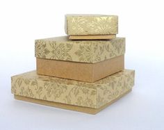 three boxes stacked on top of each other with gold foiling and floral designs in them