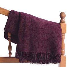 a wooden headboard with a purple blanket on it's back and wood posts