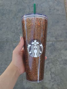 a person holding up a starbucks cup with glitter on it