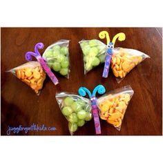 four bags filled with fruit and butterflies on top of a wooden table next to an apple