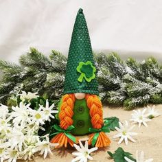 a green and orange gnome sitting on top of white flowers