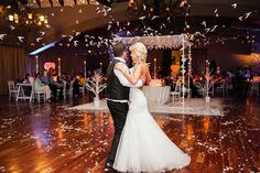 a bride and groom are dancing on the dance floor at their wedding reception with confetti falling all around them