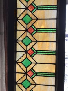 an old stained glass window with green and red geometric designs on the bottom half of it