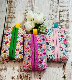 three purses with flowers on them sitting next to each other in front of a white wooden background