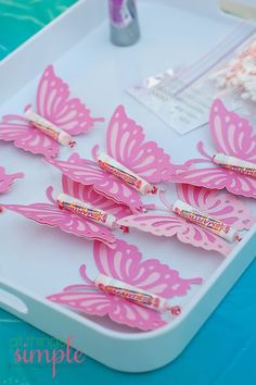 pink butterflies are sitting on a tray next to some toothbrushes and other items