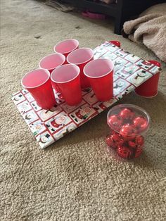 red cups sitting on top of a carpet next to a tray filled with candy canes