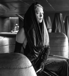 black and white photograph of a woman sitting on the back of a bus wearing a hoodie