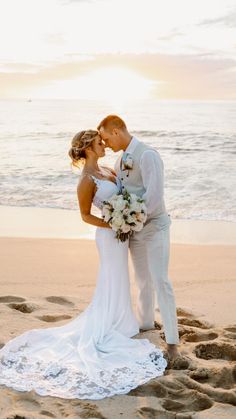 a bride and groom kissing on the beach in front of the ocean at sunset or sunrise