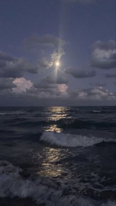 the moon is shining over the ocean with waves