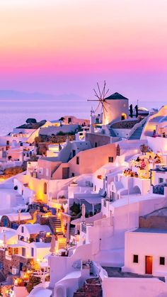 the sun is setting over white buildings and windmills in oiai, greece