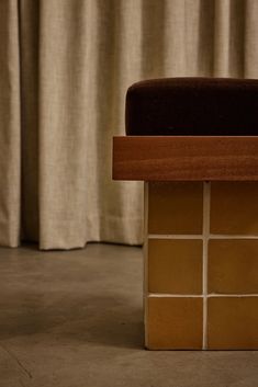 a close up of a wooden bench with a brown cushion on it's back