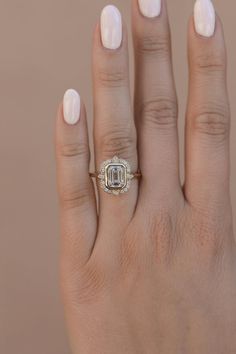 a woman's hand with a diamond ring on her left hand, and a white manicured nail