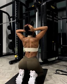 a woman sitting on top of a black mat in front of a gym machine