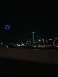 the city skyline is lit up at night with bright lights in the sky and buildings behind it