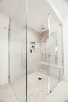 a walk in shower sitting next to a white tiled wall and floor with glass doors