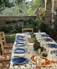 an outdoor table set with blue plates and glasses