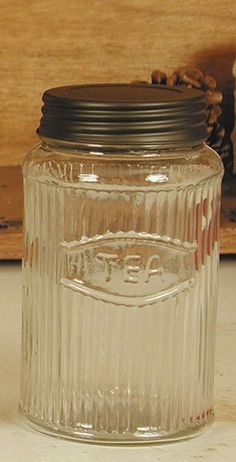 a glass jar with a black lid sitting on a table next to a piece of wood