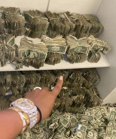 a person pointing at stacks of money on a shelf