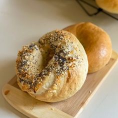 two bagels sitting on top of a wooden cutting board next to eachother