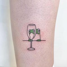 a person with a tattoo on their leg has a wine glass in front of them