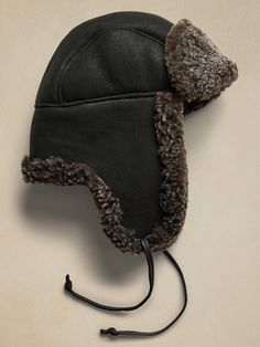 Indulgently soft and warm, this hat is cut with the suede side facing, leaving the inside lined with sumptuous shearling to stay warm during the coldest days.  Complete with ties to raise or lower the ear flaps as the weather allows.  Crown Cap: Since 1934, the expert craftsmen at Canada's Crown Cap have produced superior headwear and accessories, working with exquisite materials to create exceptional and stylish cold-weather essentials.  Ear flaps and chin strap.  Fully lined.  Made in Canada. Winter Windproof Leather Hat, Leather Hat With Ear Flaps For Outdoor, Winter Leather Windproof Hat, Leather Hats With Faux Fur Lining And Ear Flaps, Sheepskin Hats With Ear Flaps For Outdoor, Shearling Hat With Faux Fur Lining And Ear Flaps, Sheepskin Hat With Faux Fur Lining And Ear Flaps, Sheepskin Outdoor Hat With Ear Flaps, Crown Cap