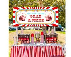 a circus themed birthday party with red and white striped table cloths, popcorn buckets, candy boxes and carnival sign