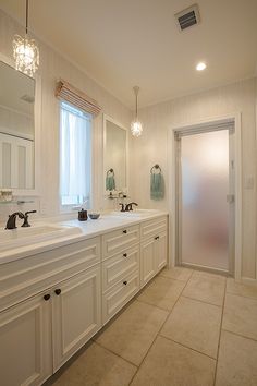 a large bathroom with two sinks, mirrors and lights on the ceiling is shown in white