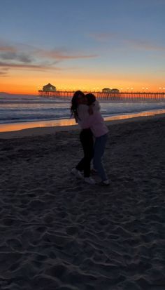 two people kissing on the beach at sunset