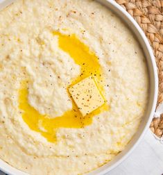 a white bowl filled with mashed potatoes and butter on top of a wicker place mat